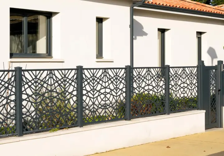 Nowoczesne, ciekawe ogrodzenia posesji z metalowymi panelami o geometrycznym wzorze liści. Elegancko oddzielają dom od ulicy.