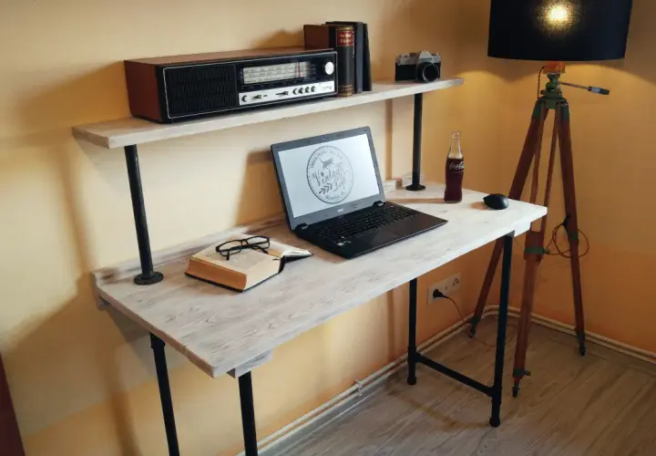 Stylowe biurko z palet, z laptopem, książką i okularami, dopełnione lampą i radiem retro.