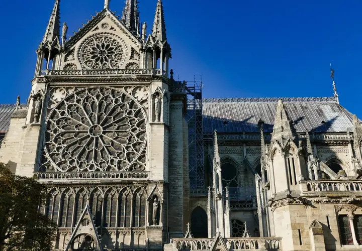 Katedra Notre-Dame z rozetą i wieżyczkami na tle błękitnego nieba.