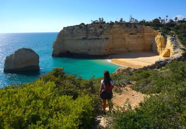 Una mujer admira las impresionantes calas del Algarve, con sus acantilados dorados y aguas turquesas.