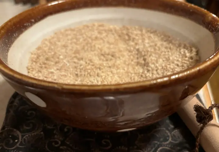A bowl of gomo shio, a Japanese seasoning, sits on a patterned cloth.