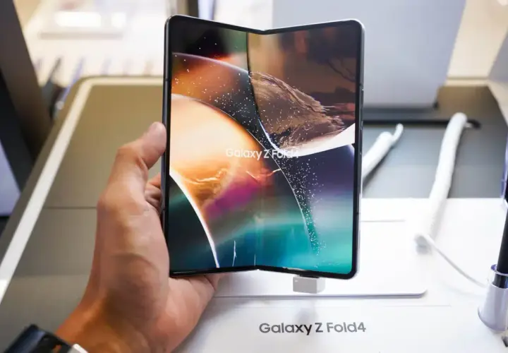 Dłoń trzyma rozłożony smartfon Galaxy Z Fold4, jeden z największych smartfonów na rynku, z kolorową tapetą.