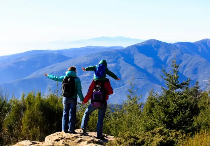 Familia disfrutando de las rutes montseny, con un niño a hombros, contemplando el paisaje montañoso.