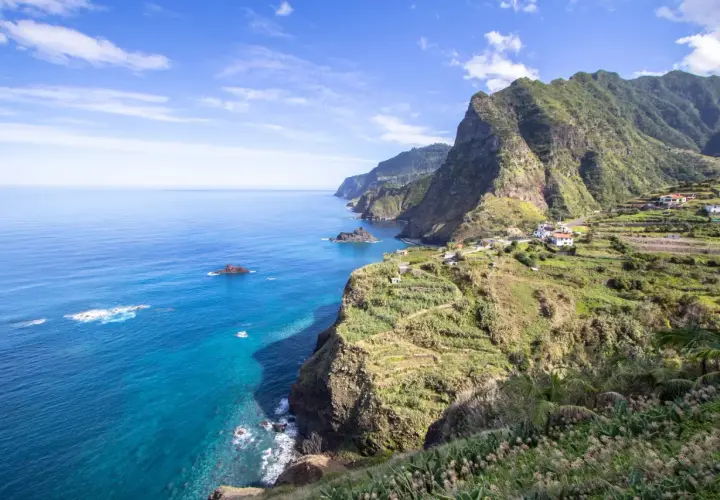 Malownicze wybrzeże Madera wyspa z zielonymi tarasami i białymi domkami, wpadające do turkusowego oceanu.