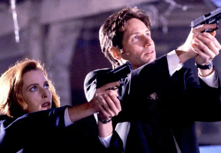 Z archiwum X: Scully i Mulder w akcji, celują z broni. Tajemnica czeka.