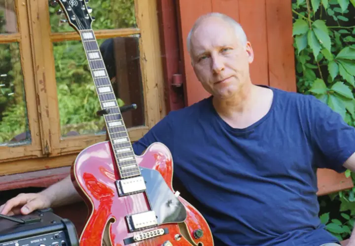 Kuba Sienkiewicz z zespołem przygotowuje się do koncertu. Czerwona gitara i wzrok pełen skupienia.