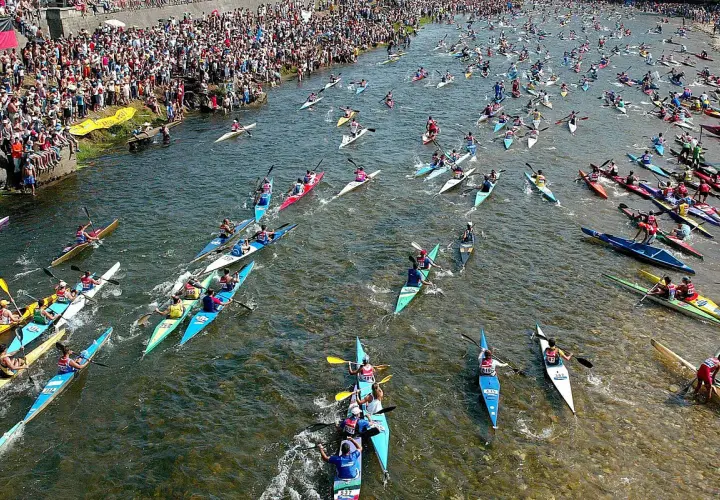 Multitudinaria fiesta de las piraguas en un río lleno de deportistas compitiendo en sus canoas.