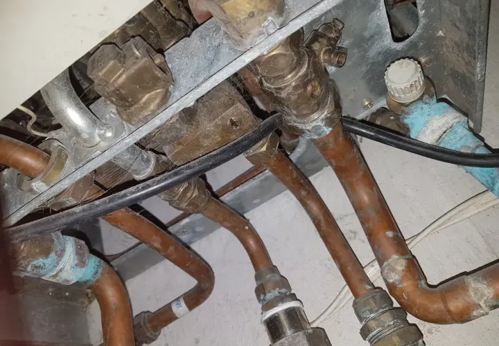 Instalacja pieca gazowego Vaillant z miedzianymi rurami. Widoczne przyłącza i zawory, być może problem ze słabym ciśnieniem ciepłej wody.