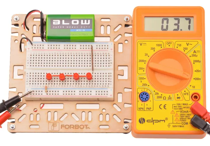 Zestaw do eksperymentów z elektroniką: płytka stykowa, bateria 9V, multimetr i rezystor.