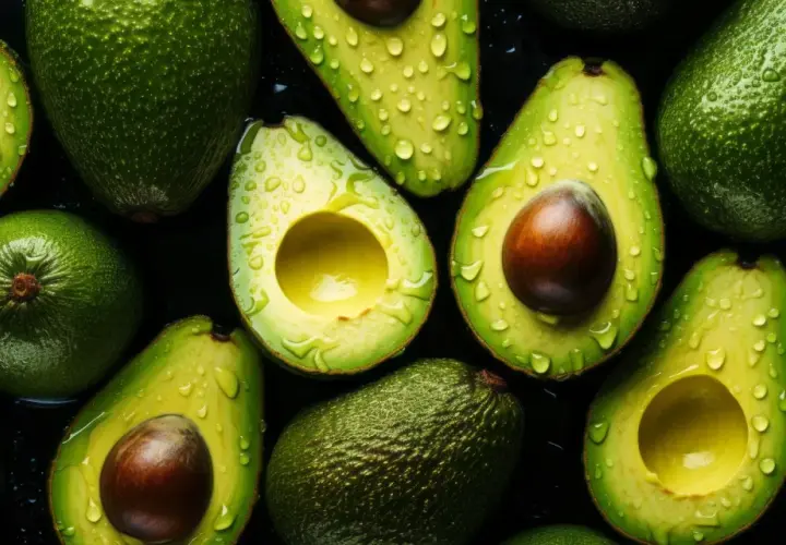 Aguacates frescos y jugosos, cortados y enteros, con gotas de agua, resaltando sus increíbles propiedades nutritivas.