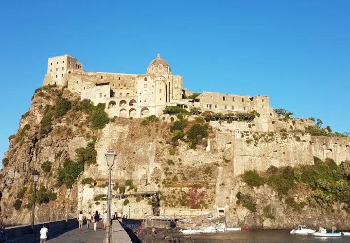 Il Castello Aragonese di Ischia, con i suoi orari e prezzi da scoprire, domina la roccia. Un ponte conduce all'imponente fortezza.