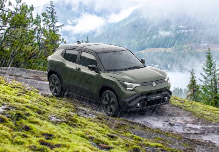 Grön Suzuki Vitara med automatisk växellåda kör på en mossig, stenig sluttning i regn.