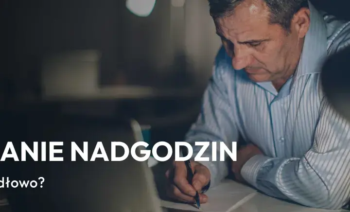 Mężczyzna pracuje po godzinach, rozliczając nadgodziny. Na ekranie laptopa widać napis "Rozliczanie nadgodzin".