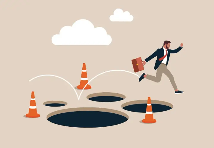Un homme d'affaires saute par-dessus des trous, symbolisant les dangers du processus d'achat immobilier.