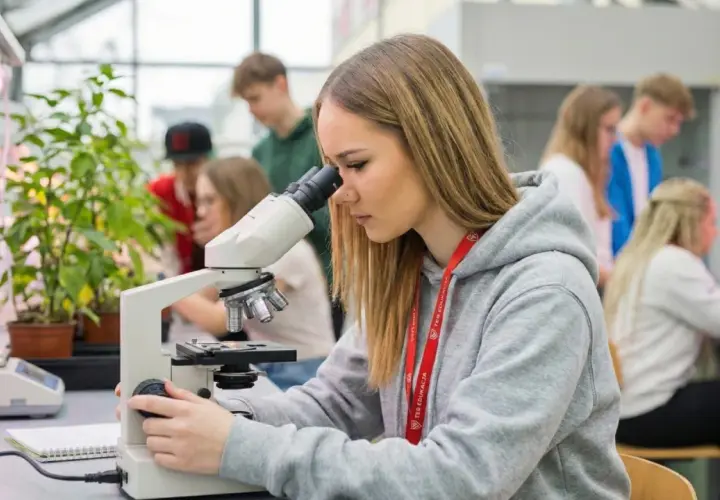 Młoda technik ochrony środowiska bada próbki pod mikroskopem w laboratorium.