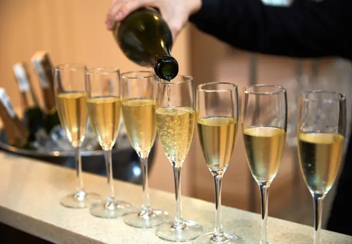Eine Flasche italienischer Champagner wird in eine Reihe von Gläsern eingeschenkt.