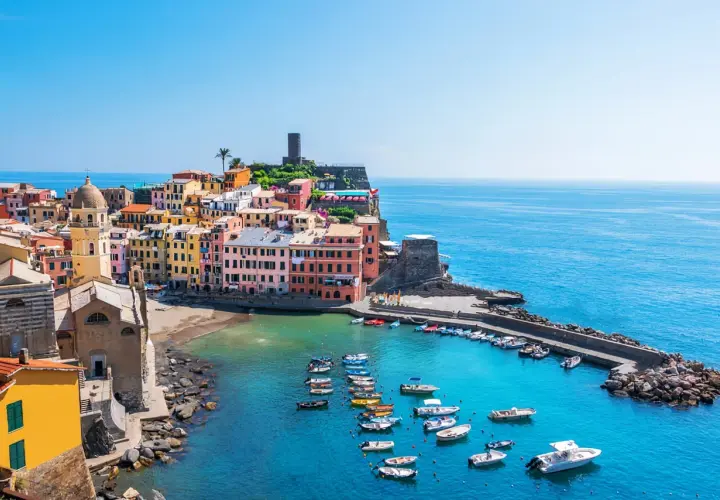 Vue pittoresque des 5 Terres en camping-car : maisons colorées, église, port animé et mer azur.