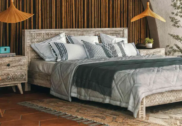 A cozy bedroom with a carved wooden bed, featuring decorative pillow shams. Can you sleep on pillow shams? Yes, they add comfort and style.