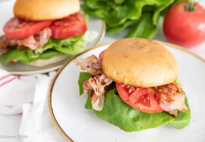 Dwa pyszne BLT na talerzach, z chrupiącym bekonem, soczystymi pomidorami i świeżą sałatą. Idealne na szybki lunch.