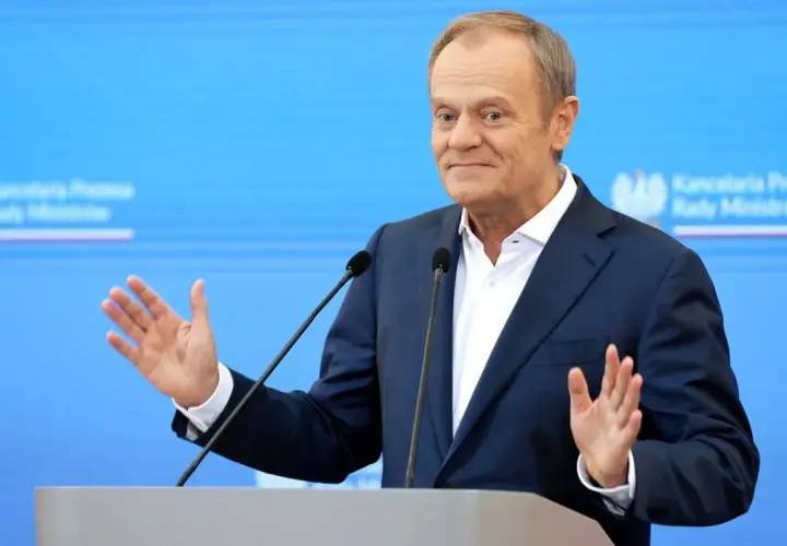 Donald Tusk przemawia, gestykulując. W tle logo Kancelarii Premiera. Czy zastanawiasz się, ile zarabia Tusk miesięcznie?