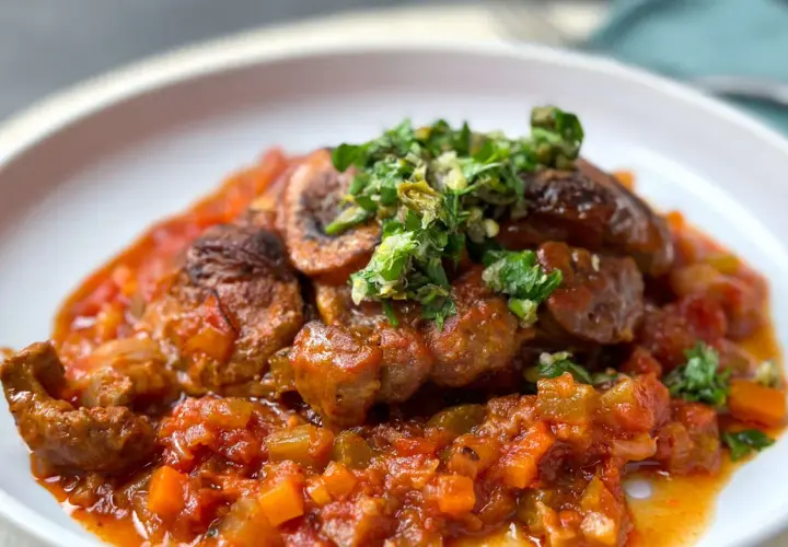 Herzhaftes Ossobuco mit einer reichhaltigen Tomaten-Gemüse-Sauce und frischer Kräuter-Gremolata als Beilage.