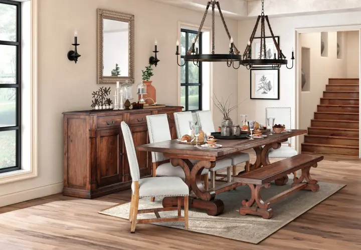 A rustic dining room featuring a dark wood table with ornate legs, upholstered chairs, and a matching bench. This sturdy, beautiful wood is the best wood for kitchen table.