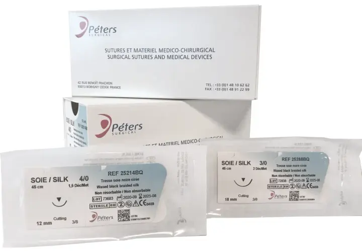 Opakowania z szwami chirurgicznymi Peters Surgical. Widać dwa pakiety z szwami jedwabnymi, w tym jeden z igłą tnącą.