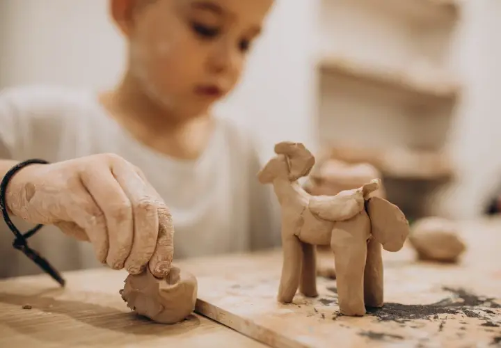 Niño de 2-3 años creando un caballito con arcilla. Divertidas actividades con arcilla para pequeños artistas.
