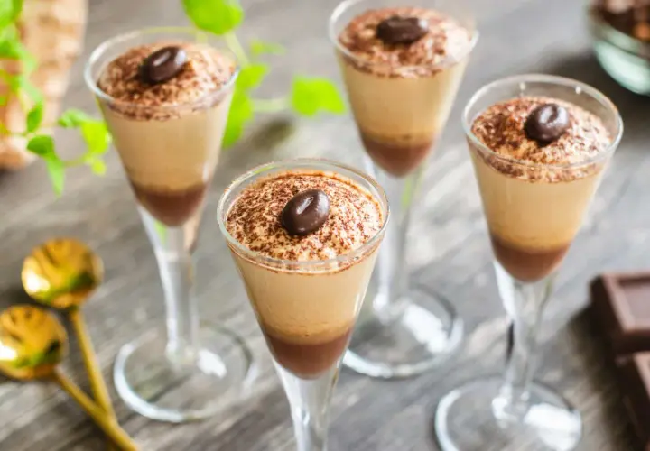 Quattro bicchieri di deliziosa mousse al caffè, spolverata di cacao e guarnita con un chicco di caffè.