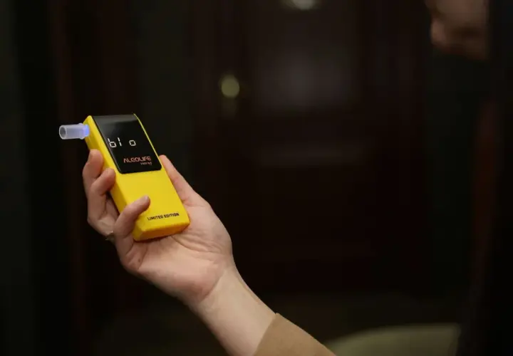 Dłoń trzyma żółty alkomat z wyświetlaczem. Czy w Żabce są alkomaty? Ten model jest limitowaną edycją.