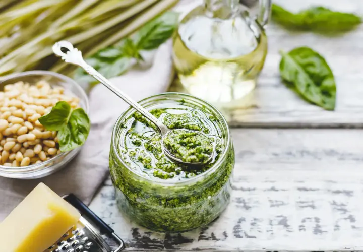 Pesto bazyliowe w słoiku, obok orzeszki piniowe, ser parmezan i oliwa. Idealne do makaronu, na grzanki i do sałatek.