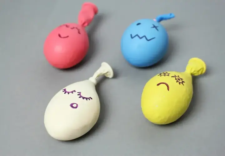 Cztery kolorowe balony z narysowanymi buźkami, gotowe do zabawy. Prosty sposób, jak zrobić gniotka.
