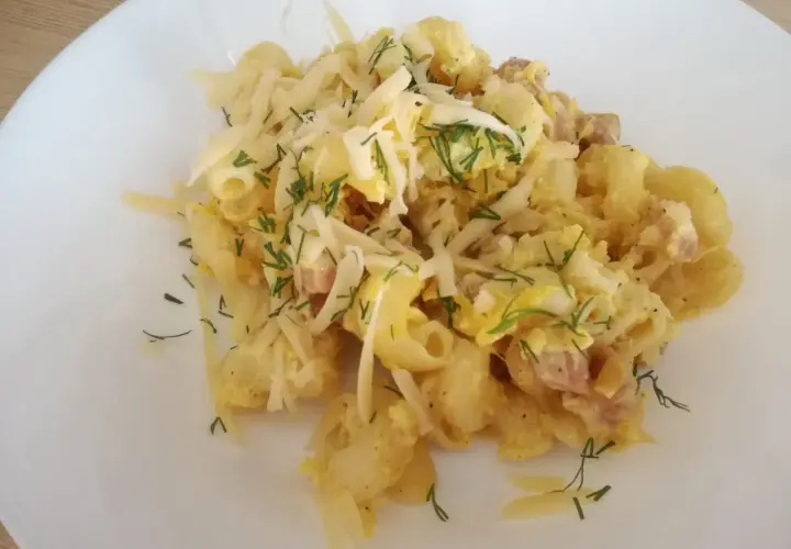 Pyszna carbonara z cukinią, makaronem, boczkiem i parmezanem, posypana świeżym koperkiem.