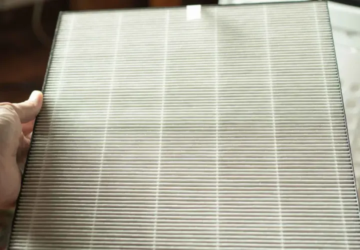Mano sosteniendo un filtro HEPA. Si te preguntas como limpiar filtro HEPA no lavable, este es el tipo de filtro que debes reemplazar.