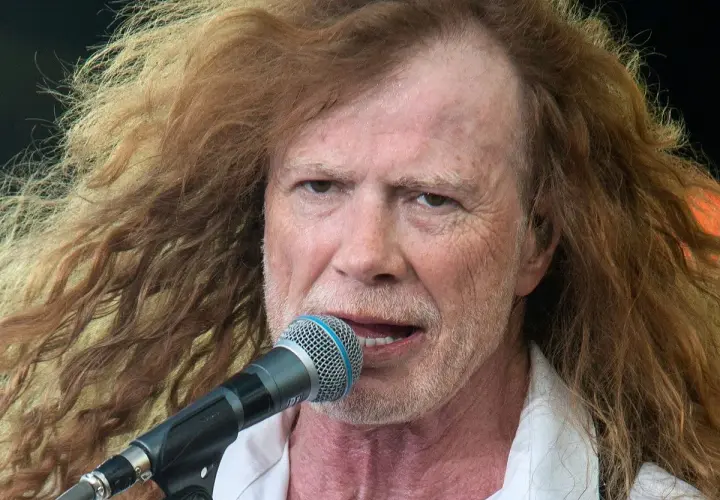 Dave Mustaine young, z burzą rudych włosów i mikrofonem przed ustami, śpiewa na scenie.