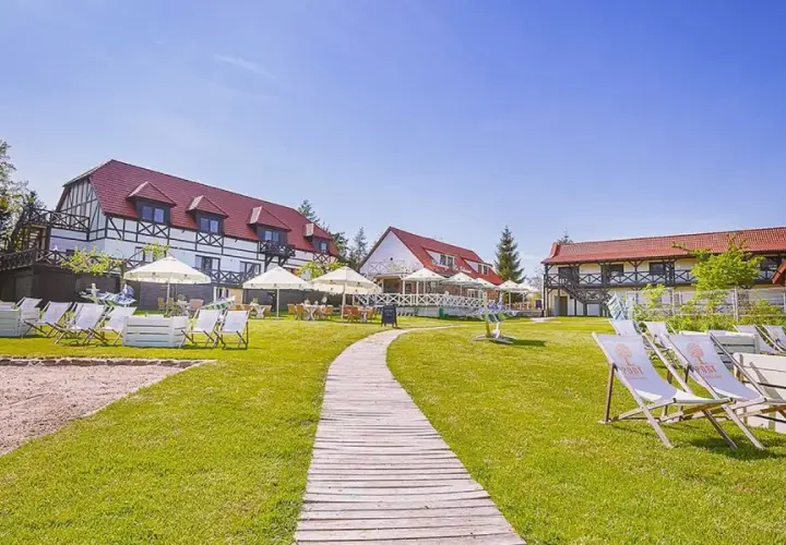 Słoneczny dzień na Mazurach. Urokliwe mazurskie miejscowości zapraszają do wypoczynku. Leżaki i parasole czekają na gości przy hotelu.
