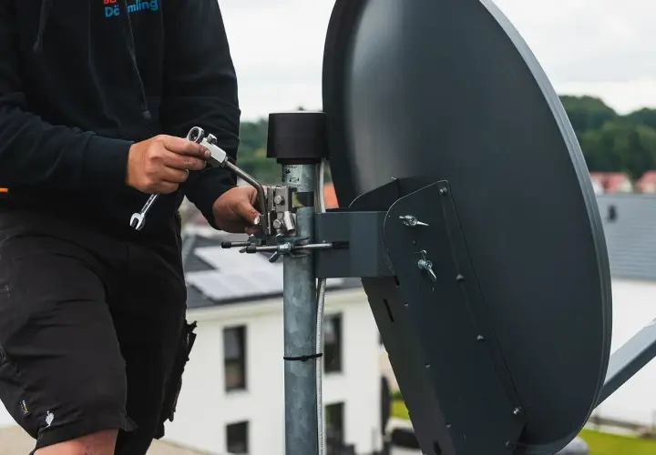 Technik ustawia antenę naziemną, używając klucza. Można to zrobić za pomocą telefonu, by uzyskać najlepszy sygnał.