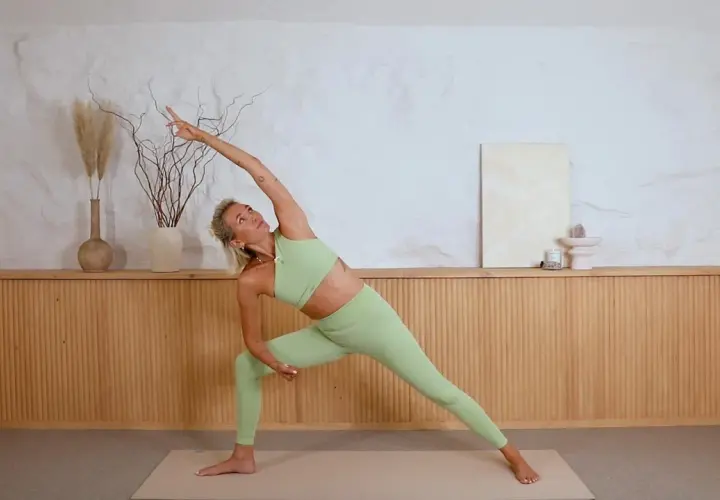 Josefine i en yoga-pose, Utbrett vinkel, med armen sträckt över huvudet.