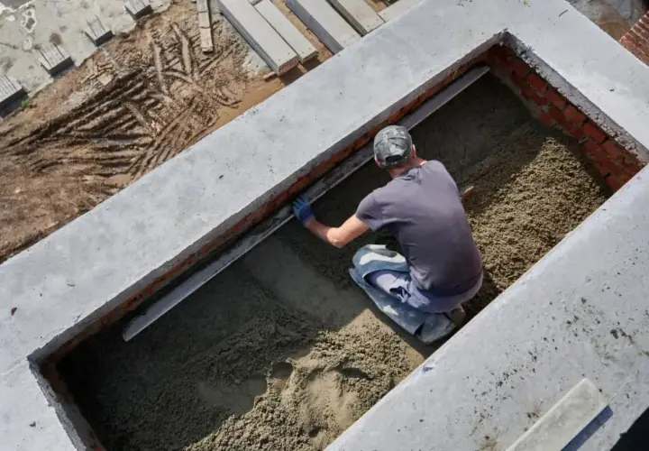 Budowlaniec wyrównuje podsypkę pod fundament. Solidny fundament to podstawa każdej budowy.