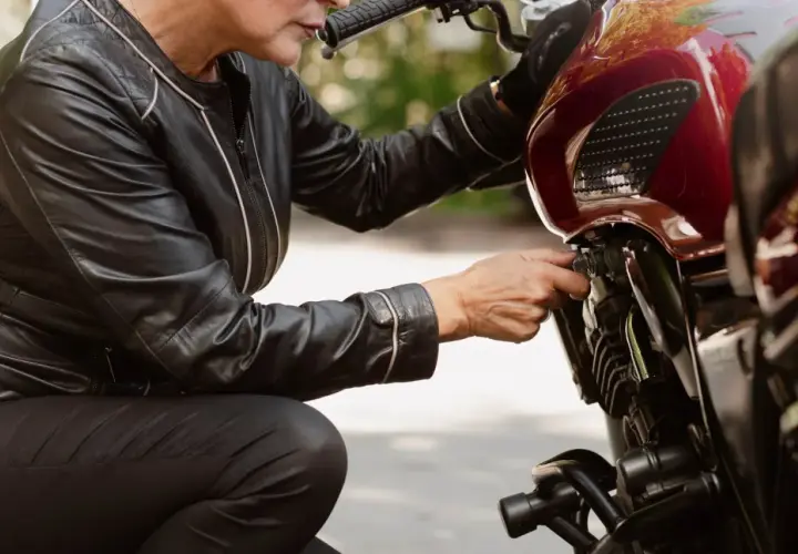 Kobieta w skórzanej kurtce sprawdza regulator napięcia alternatora w motocyklu.