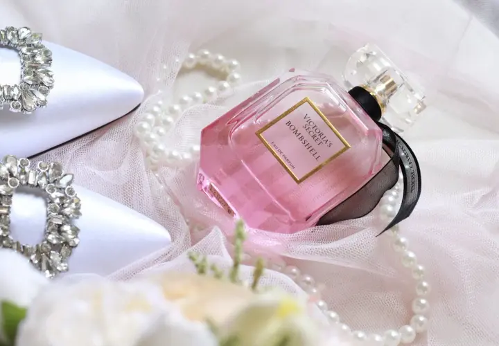Eleganckie białe buty z kryształkami, różowe oznaczenia perfum Victoria's Secret Bombshell i perły na delikatnym tiulu.