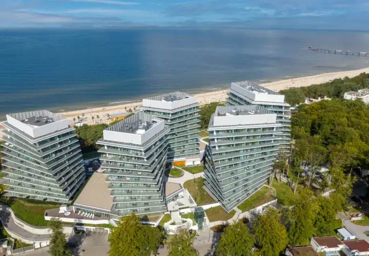 Nowoczesny wave resort z tarasami i widokiem na morze. Architektura idealnie wkomponowana w nadmorski krajobraz.