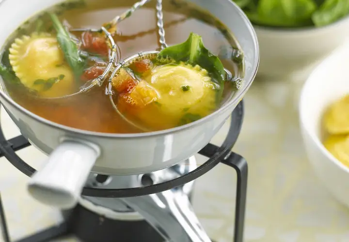 Raviolis dans un bouillon, accompagnés de légumes verts et de tomates. Une délicieuse fondue viande blanche à déguster.
