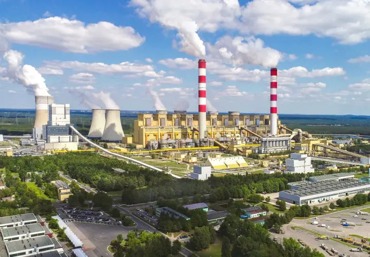 Ogromna elektrownia Bełchatów z kominami i chłodniami, emitująca białe kłęby pary. Zastanawiasz się, ile węgla spala elektrownia Bełchatów?