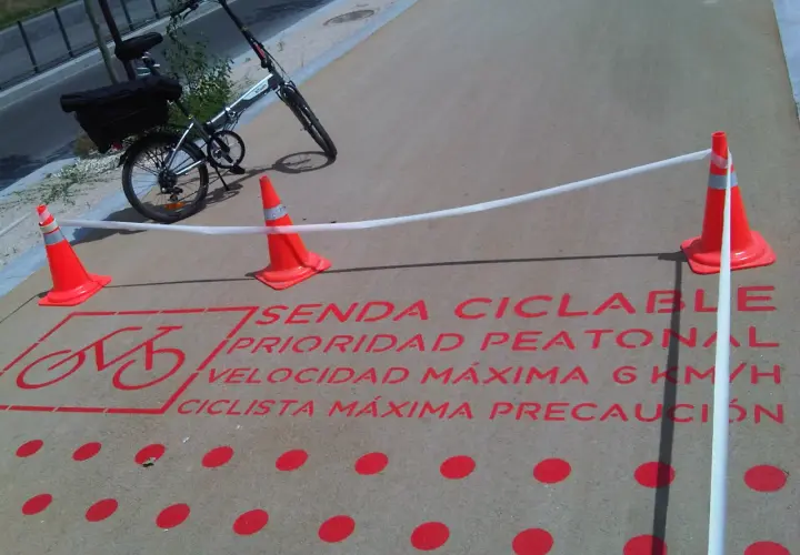 Bicicleta plegable en sendas ciclables con señalización de prioridad peatonal y límite de velocidad.