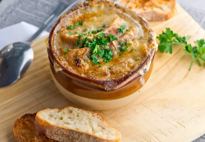 Soupe à l'oignon gratinée, un classique réconfortant. Croutons dorés, fromage fondu et persil frais. Parfait pour une recette maison.