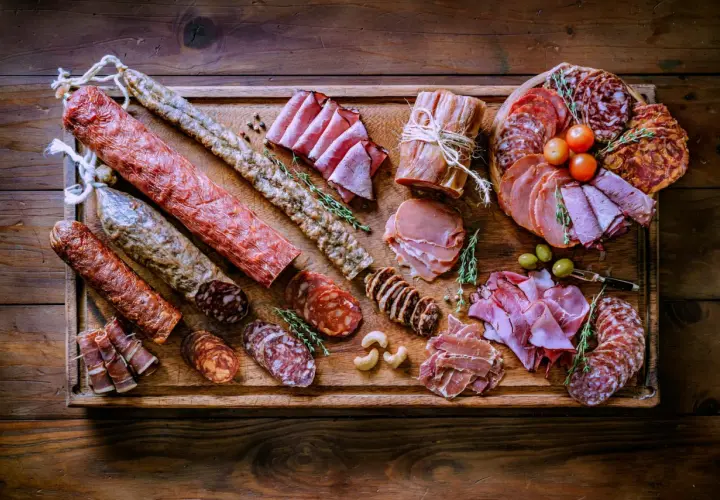 Bei taglieri di salumi e formaggi, un'abbondante selezione di prelibatezze italiane su un tagliere di legno rustico.