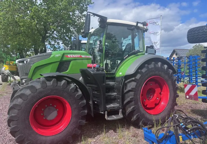 Zielony traktor Fendt 930 Vario z czerwonymi felgami, gotowy do pracy na polu.