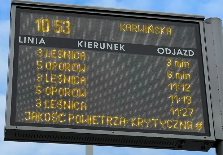 Tablica informacyjna z rozkładem jazdy MPK i informacją o krytycznej jakości powietrza.