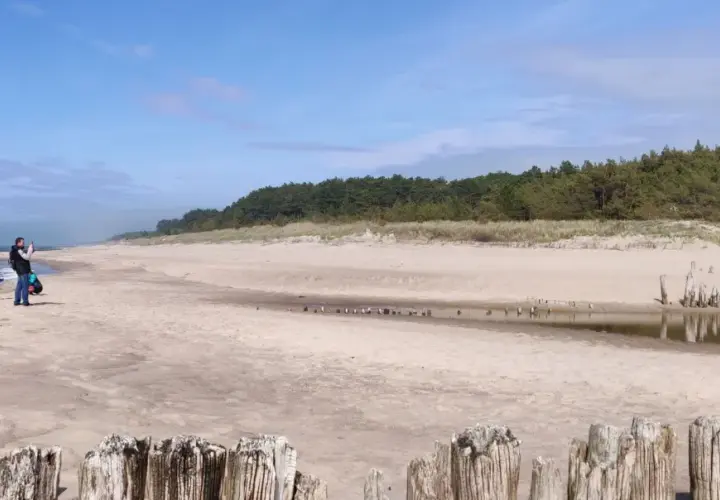 Piękna plaża w Dąbkach, idealne miejsce na rodzinne atrakcje. Ojciec z dzieckiem spacerują brzegiem morza.